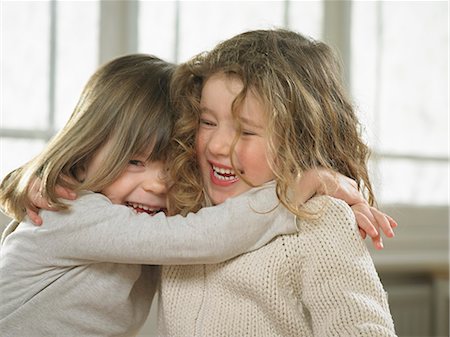 simsearch:649-06716556,k - Smiling girls hugging indoors Foto de stock - Royalty Free Premium, Número: 649-06716532