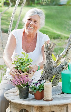 senior gardening looking at camera - Older woman arranging flowers outdoors Stock Photo - Premium Royalty-Free, Code: 649-06716677