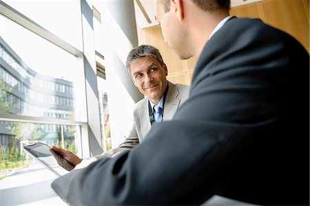 simsearch:649-06716753,k - Businessmen using tablet computer at desk Stock Photo - Premium Royalty-Free, Code: 649-06716761