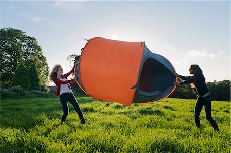 simsearch:649-06489735,k - Teenage girls pitching tent in field Photographie de stock - Premium Libres de Droits, Code: 649-06716856