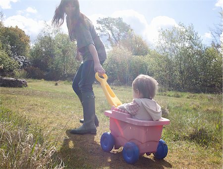 rain boots and child and mom - Mother pulling toddler girl in wagon Stock Photo - Premium Royalty-Free, Code: 649-06716887