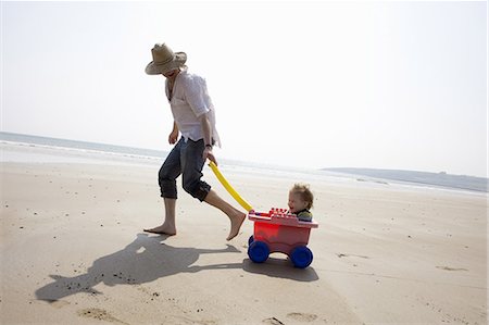 sunhat - Father with daughter in wagon on beach Stock Photo - Premium Royalty-Free, Code: 649-06716890