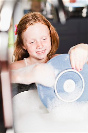 Smiling girl washing plate in sink Stock Photo - Premium Royalty-Free, Code: 649-06716982