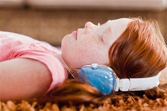 Girl listening to headphones on carpet Stock Photo - Premium Royalty-Free, Image code: 649-06717011