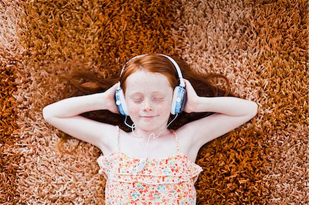 Girl listening to headphones on carpet Stockbilder - Premium RF Lizenzfrei, Bildnummer: 649-06717012