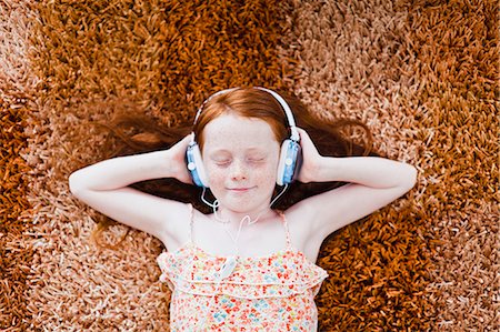 earphones girl - Girl listening to headphones on carpet Stock Photo - Premium Royalty-Free, Code: 649-06717012