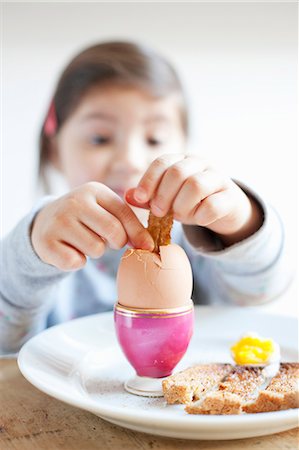 eat boiled egg - Girl dipping toast into egg at breakfast Stock Photo - Premium Royalty-Free, Code: 649-06717463