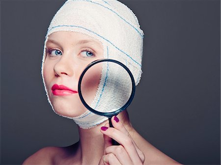 Woman in bandages with magnifying glass Stock Photo - Premium Royalty-Free, Code: 649-06717556