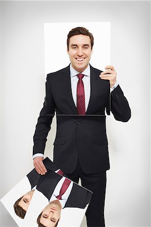 standing out from the crowd - Businessman holding happy picture over his face Stock Photo - Premium Royalty-Free, Code: 649-06717564