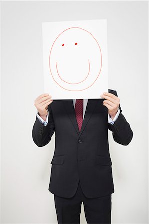 Businessman holding happy face over his face Stock Photo - Premium Royalty-Free, Code: 649-06717577