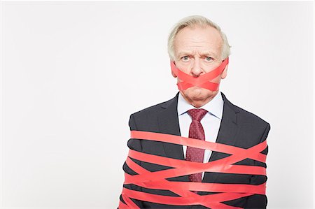 Businessman wrapped in red tape Foto de stock - Sin royalties Premium, Código: 649-06717597