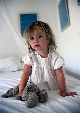 Girl holding teddy bear on bed Foto de stock - Sin royalties Premium, Código: 649-06717810