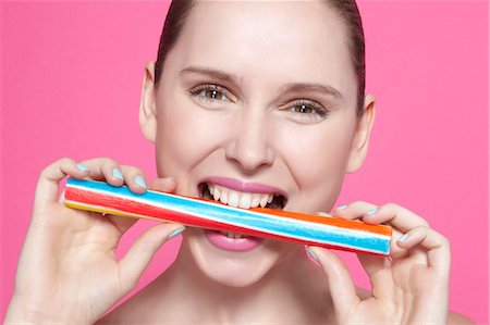 Smiling woman biting candy Stock Photo - Premium Royalty-Free, Code: 649-06717827