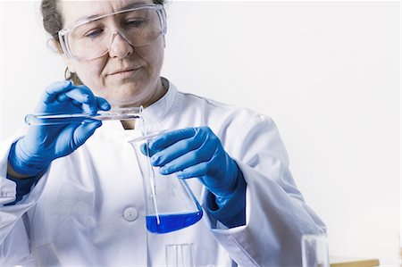 person in white coat and goggles - Scientist pouring liquid into beaker Stock Photo - Premium Royalty-Free, Code: 649-06717882