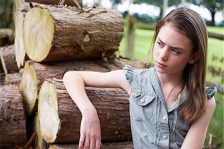 pecas - Teenage girl leaning on logs in  forest Foto de stock - Sin royalties Premium, Código: 649-06812061