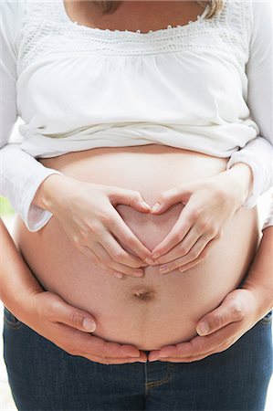 Hands in heart shape on pregnant woman's stomach Foto de stock - Sin royalties Premium, Código: 649-06812077