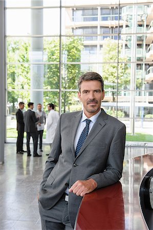 Businessman leaning against reception desk Foto de stock - Sin royalties Premium, Código: 649-06812105