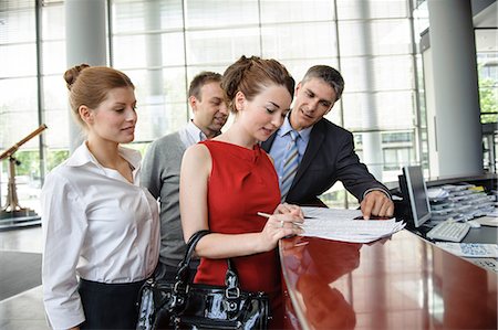 recepcionista - Woman signing agreement on reception desk surrounded by group of business people Foto de stock - Sin royalties Premium, Código: 649-06812120