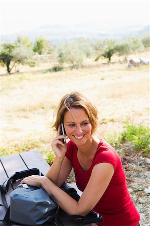 simsearch:649-06812221,k - Woman sitting at picnic bench on cell phone Photographie de stock - Premium Libres de Droits, Code: 649-06812219