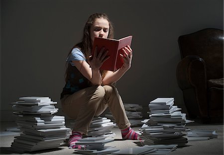 simsearch:649-06812227,k - Girl sitting on pile of books reading Fotografie stock - Premium Royalty-Free, Codice: 649-06812225