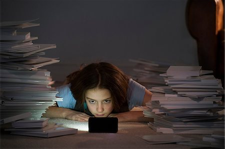 simsearch:649-06812232,k - Girl lying on front watching cell smartphone surrounded by books Photographie de stock - Premium Libres de Droits, Code: 649-06812231