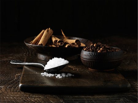Ingredients to make an Irish dry cured spiced beef joint. Sea salt, cinnamon sticks and mixed spices on dark wooden surface Photographie de stock - Premium Libres de Droits, Code: 649-06812308