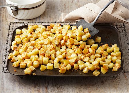 roasted (not meat) - Parmentier potatoes on baking sheet and wire rack. Maris Piper potatoes roasted in garlic and rosemary butter Stock Photo - Premium Royalty-Free, Code: 649-06812315