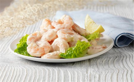 Prawn cocktail with lemon, lettuce and rose marie sauce on white wooden surface with fishing net Stock Photo - Premium Royalty-Free, Code: 649-06812321