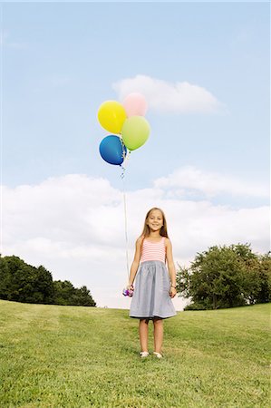 Girl holding balloons standing on grass Foto de stock - Sin royalties Premium, Código: 649-06812428