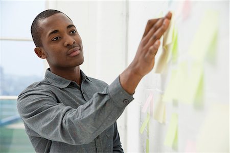 Young man sticking adhesive notes to wall Foto de stock - Sin royalties Premium, Código: 649-06812628