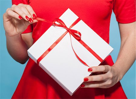 Woman opening white gift box with red bow, mid section Stock Photo - Premium Royalty-Free, Code: 649-06812641