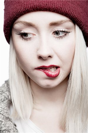 Young woman wearing red hat biting lip Fotografie stock - Premium Royalty-Free, Codice: 649-06812744