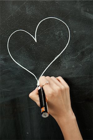 drawing on chalkboard - Young woman drawing heart on blackboard Stock Photo - Premium Royalty-Free, Code: 649-06812756