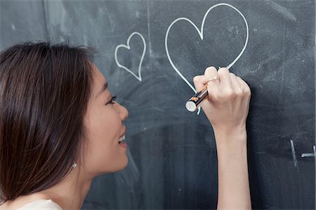 Young woman drawing heart on blackboard Foto de stock - Sin royalties Premium, Código: 649-06812757