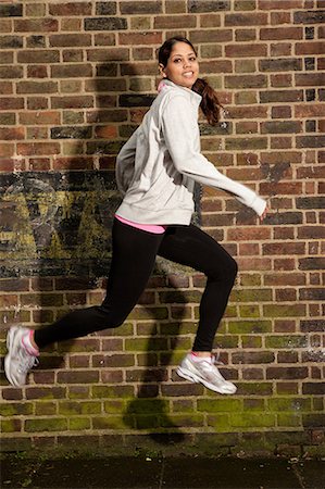 simsearch:649-06812848,k - Young woman jumping by brick wall Foto de stock - Sin royalties Premium, Código: 649-06812842