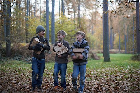 Boys walking through forest carrying wood Stock Photo - Premium Royalty-Free, Code: 649-06812969