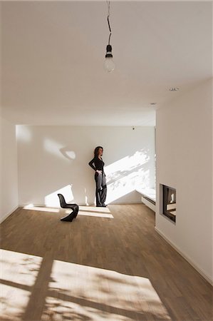 sentiment de solitude - Woman standing by wall in empty room Photographie de stock - Premium Libres de Droits, Code: 649-06829368