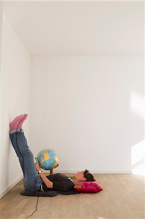 Woman lying on floor of empty room holding globe Stock Photo - Premium Royalty-Free, Code: 649-06829382