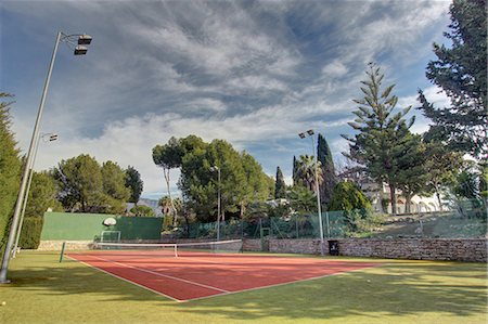 quadra de tênis - Empty tennis courts in grounds of luxury home Foto de stock - Royalty Free Premium, Número: 649-06829421