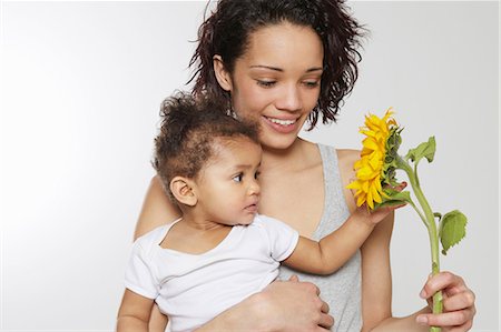 Baby girl touching sunflower held by mother in studio Stock Photo - Premium Royalty-Free, Code: 649-06829440