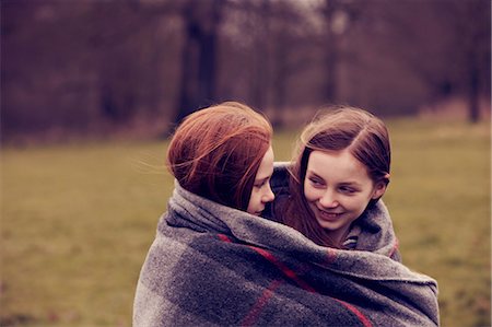 simsearch:649-06533100,k - Girls wrapped in a blanket outdoors, smiling Stock Photo - Premium Royalty-Free, Code: 649-06829596