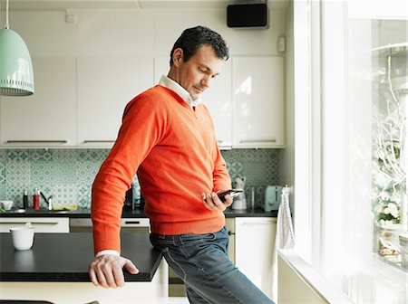 plan de travail (cuisine) - Mature man using cellphone in kitchen Photographie de stock - Premium Libres de Droits, Code: 649-06829605