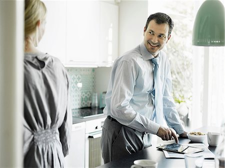 simsearch:649-06829625,k - Mature businessman using tablet and smiling in kitchen Stock Photo - Premium Royalty-Free, Code: 649-06829615