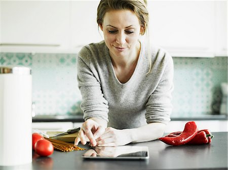 Mid adult woman using digital tablet on kitchen counter Photographie de stock - Premium Libres de Droits, Code: 649-06829621
