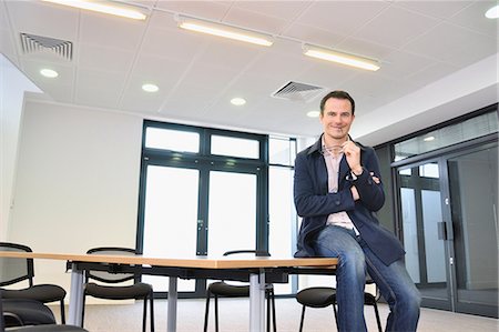 Male office worker sitting on table in office Stockbilder - Premium RF Lizenzfrei, Bildnummer: 649-06829675