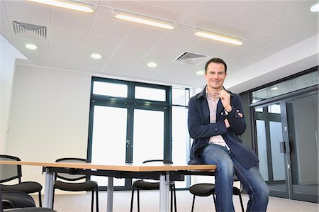 Male office worker sitting on table in office Stock Photo - Premium Royalty-Free, Code: 649-06829675