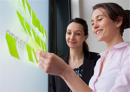 Female colleagues sticking adhesive notes on glass Stockbilder - Premium RF Lizenzfrei, Bildnummer: 649-06829678