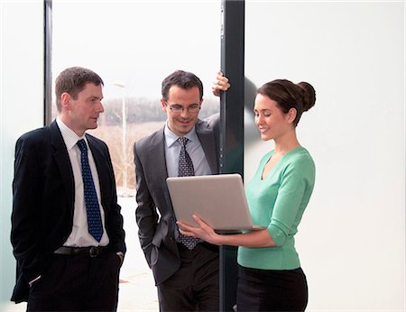 simsearch:649-06829703,k - Three colleagues talking, woman holding laptop Stock Photo - Premium Royalty-Free, Code: 649-06829698