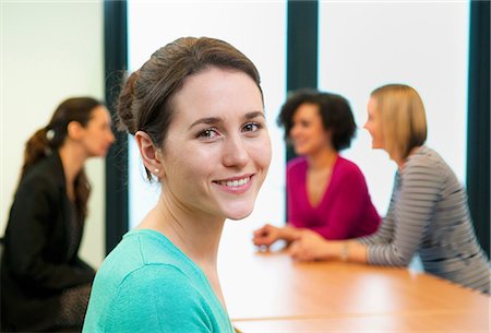 simsearch:649-06829703,k - Young woman in office with colleagues in background Stock Photo - Premium Royalty-Free, Code: 649-06829714