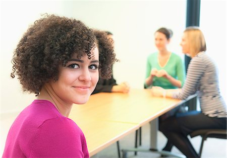 simsearch:649-06829703,k - Young woman in office with colleagues in background Stock Photo - Premium Royalty-Free, Code: 649-06829715